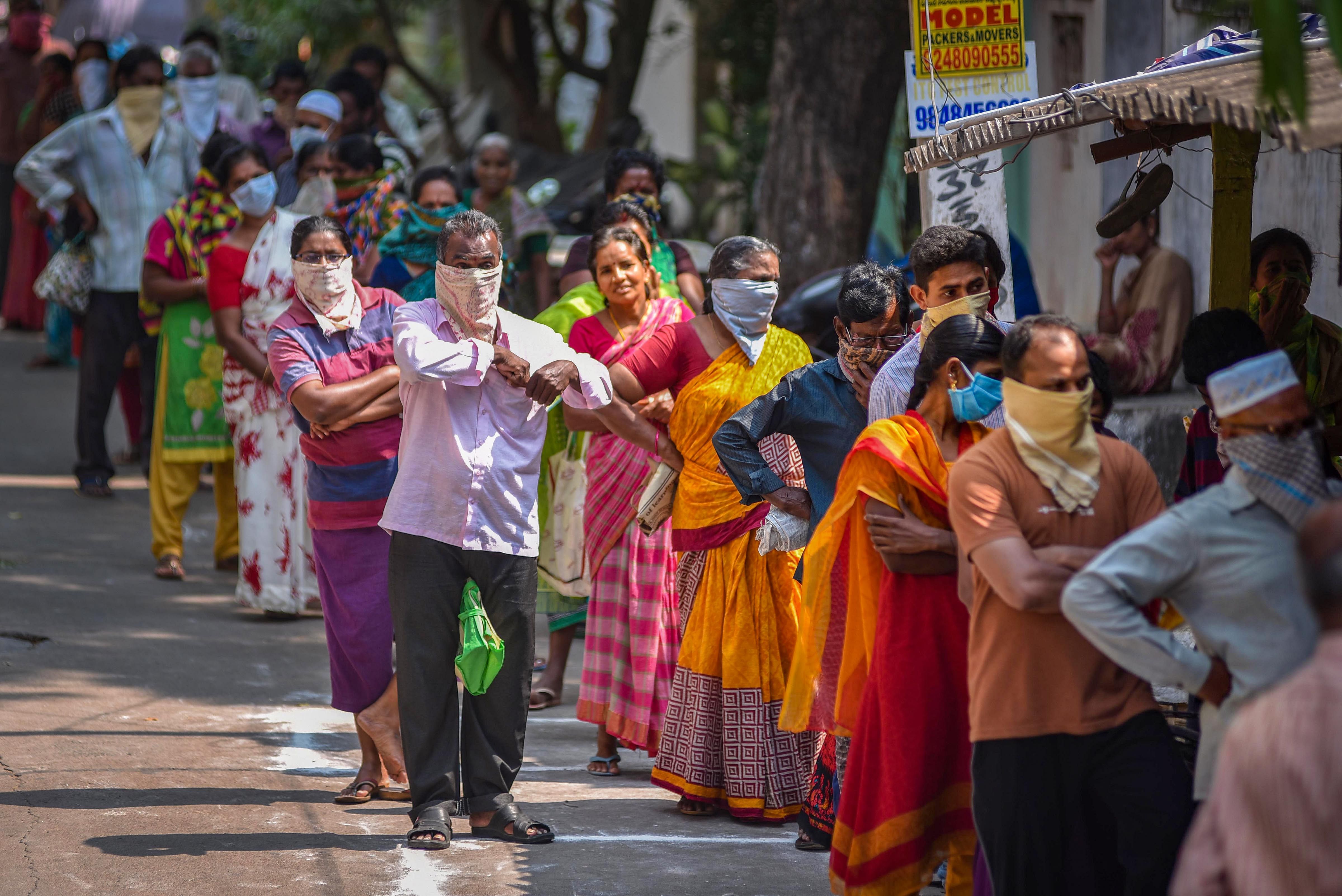 People stand in a queue to receive ration, supplied by the government, during a nationwide lockdown, imposed in the wake of coronavirus. (PTI Photo)
