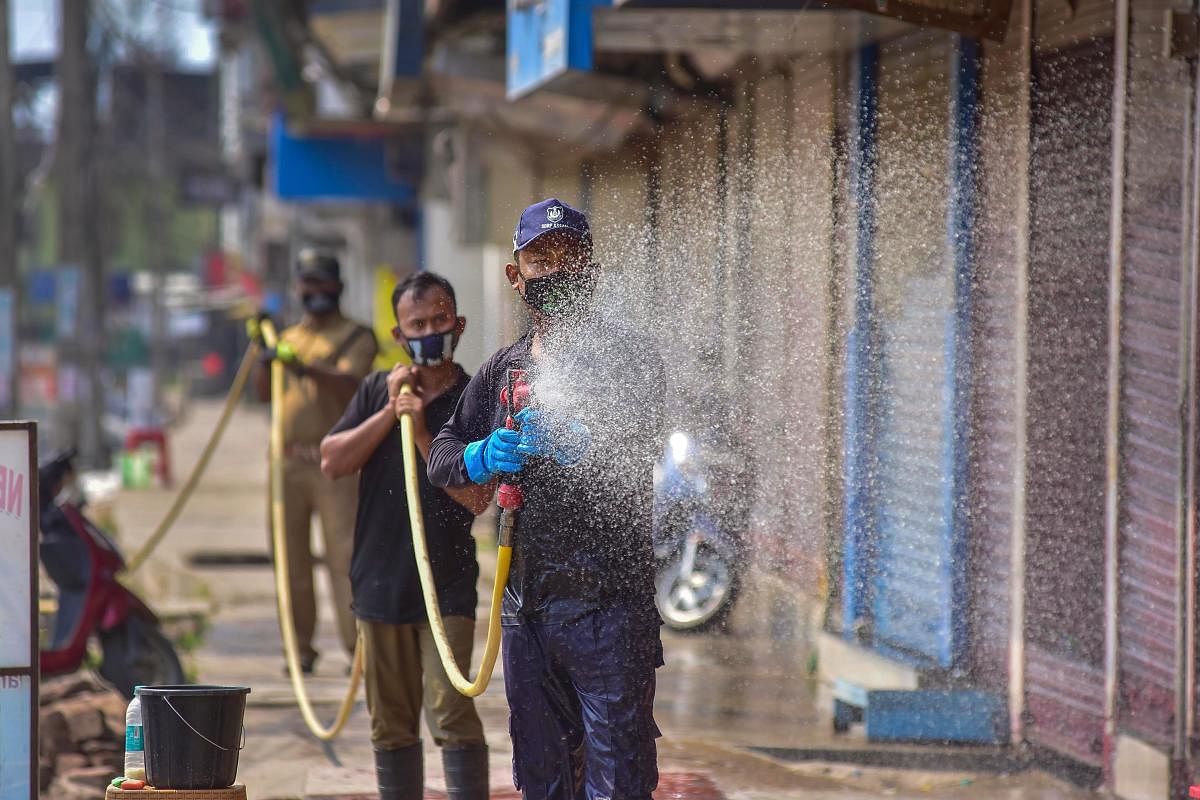 Fire brigade officials spray disinfectant outside shops in the wake of the coronavirus pandemic, during the nationwide lockdown, in Nagaon, Tuesday, March 31, 2020. (PTI Photo)
