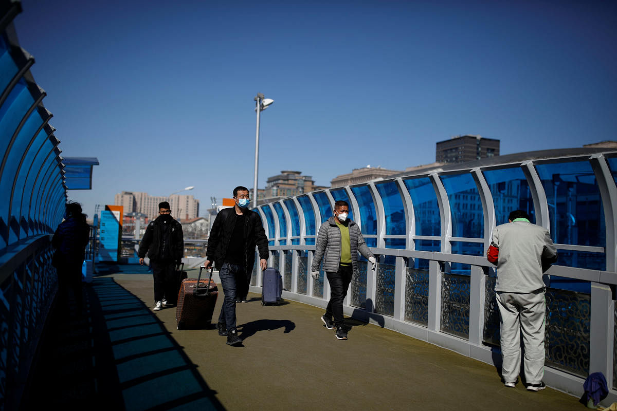 People wear face masks while walking in a footbridge near of Beijing Railway Station, following an outbreak of the coronavirus disease (COVID-19), in Beijing, China (Reuters Photo)