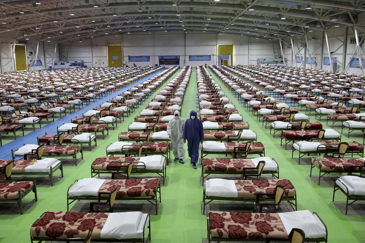  People in protective clothing walk past rows of beds at a temporary 2,000-bed hospital for COVID-19 coronavirus patients in Iran (AP Photo)