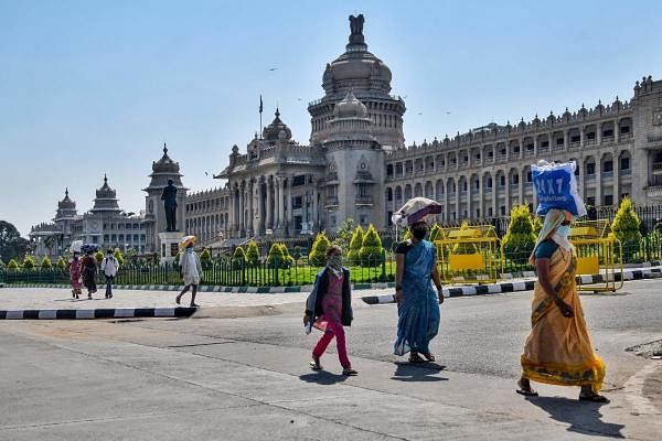 Daily wage labourers and their families carrying their belongings walk past the Vidhana Soudha building as they leave the city for their hometown during a government-imposed nationwide lockdown against the COVID-19 coronavirus, in Bangalore on March 31, 2020. (Photo by Manjunath Kiran / AFP)