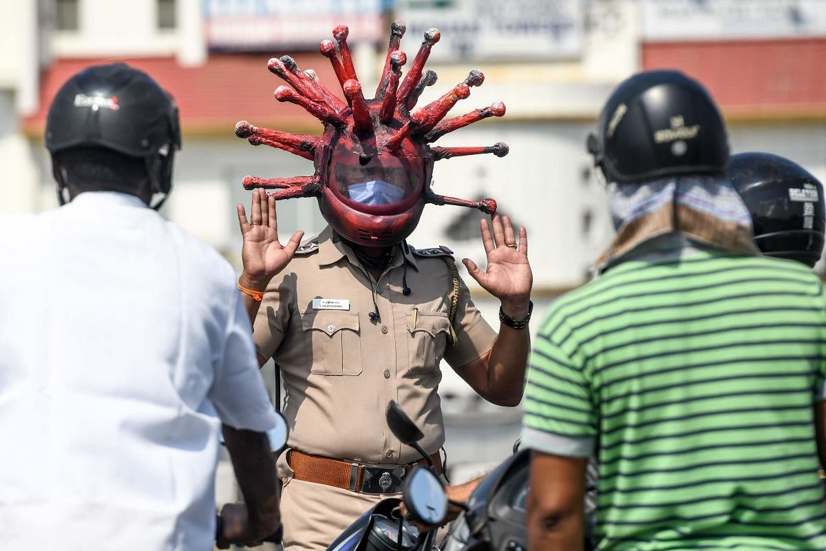 Police inspector Rajesh Babu (C) wearing a coronavirus-themed helmet speaks to motorists at a checkpoint during a government-imposed nationwide lockdown as a preventive measure against the COVID-19 coronavirus in Chennai. (AFP Photo)
