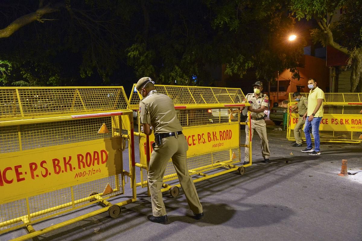 Police officials seal the Bengali market area after a case of coronavirus was reported, during the lockdown, New Delhi, Wednesday, April 8, 2020. (PTI Photo)