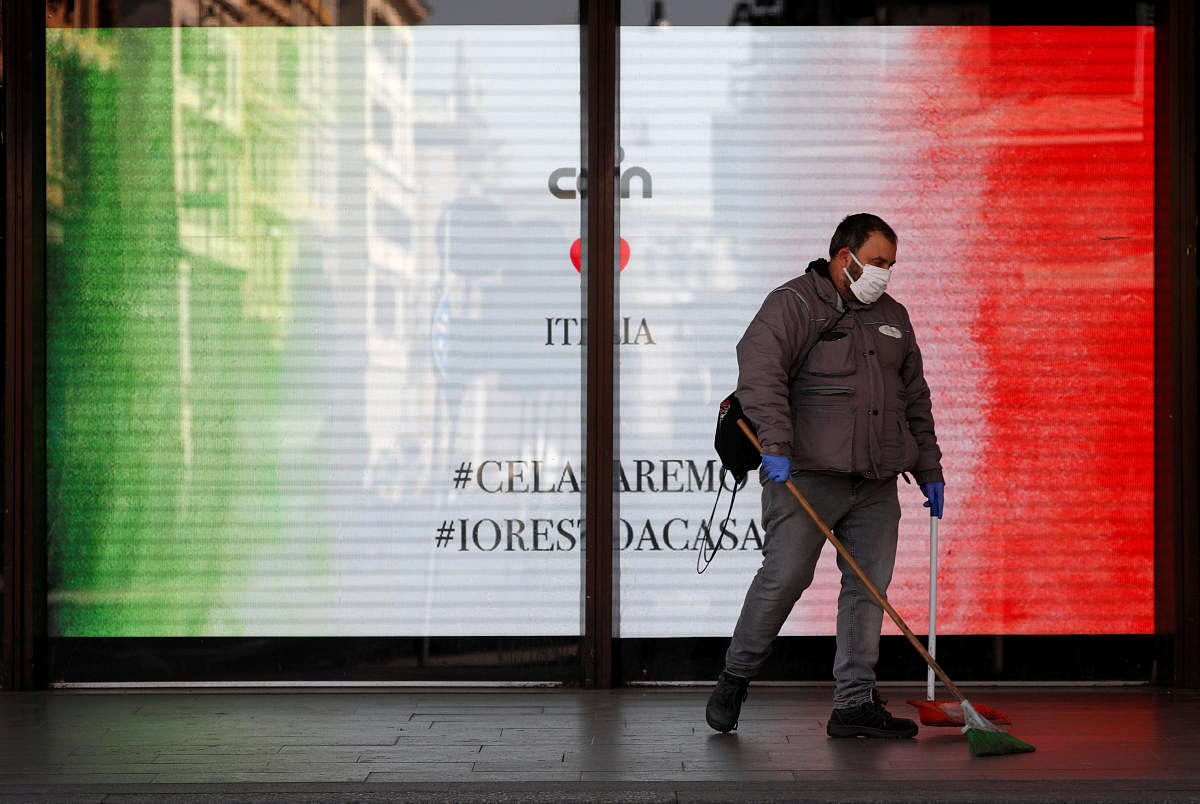 A worker in a protective mask cleans near a banner with the Italian flag placed behind a window of the Termini train station, as the spread of the coronavirus disease (COVID-19) continues, in Rome, Italy April 7, 2020. Credit: Reuters Photo