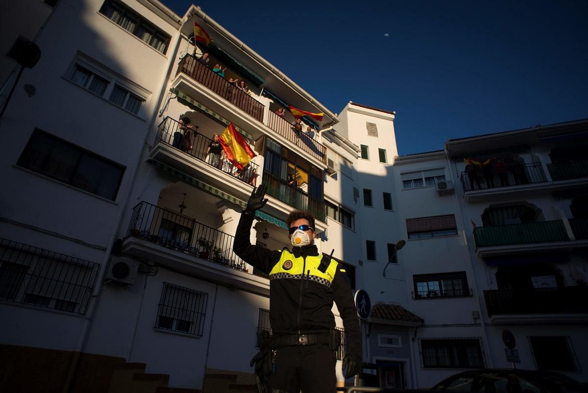 A police officer waves as people applaud to thank healthcare workers dealing with the COVID-19 coronavirus hangs in Ronda on April 3, 2020 during a national lockdown to prevent the spread of the COVID-19 coronavirus. Credit: AFP Photo