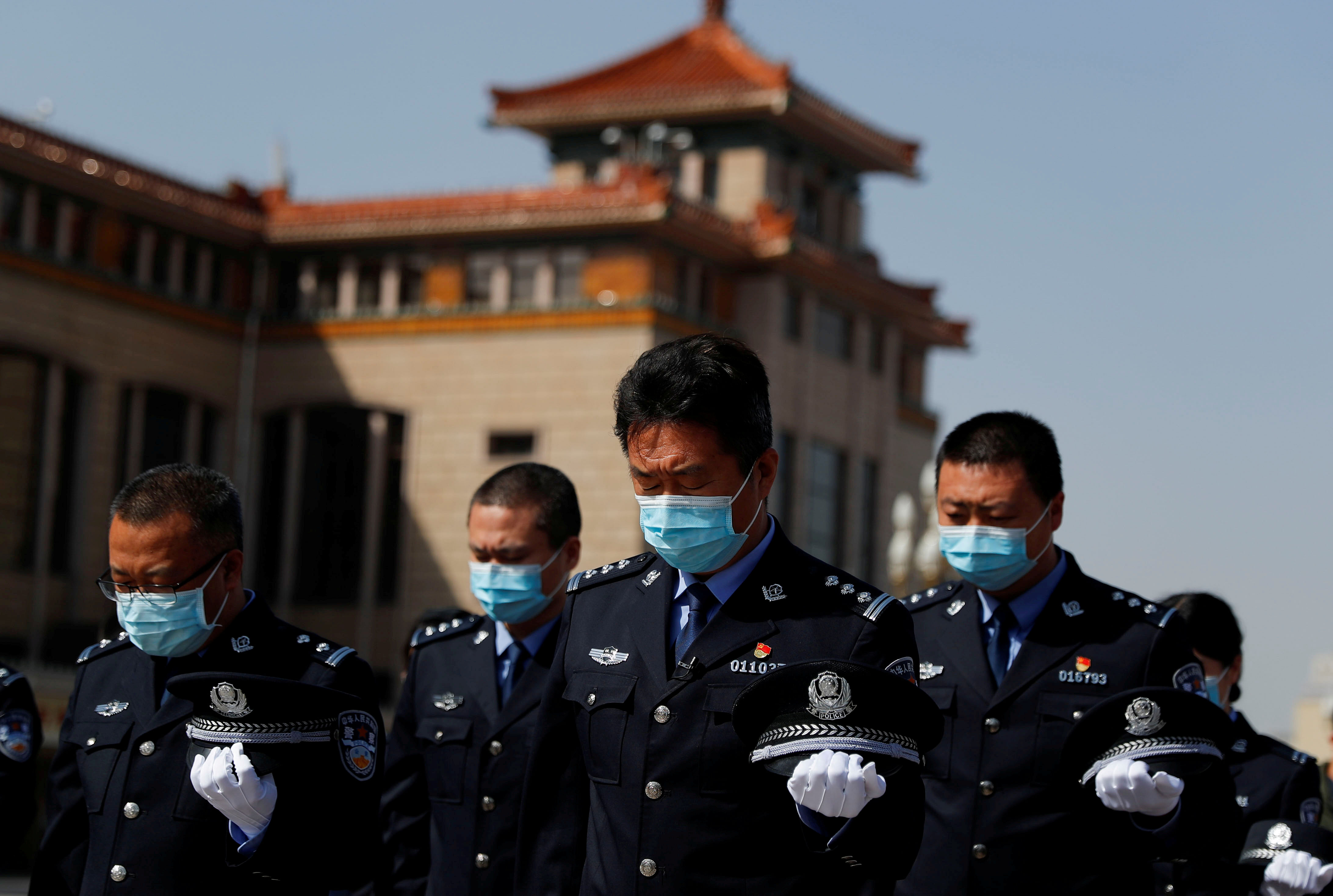Security personnel wearing face masks stand to pay tribute as China holds national mourning for those who died of the coronavirus disease (COVID-19). (Credit: Reuters)