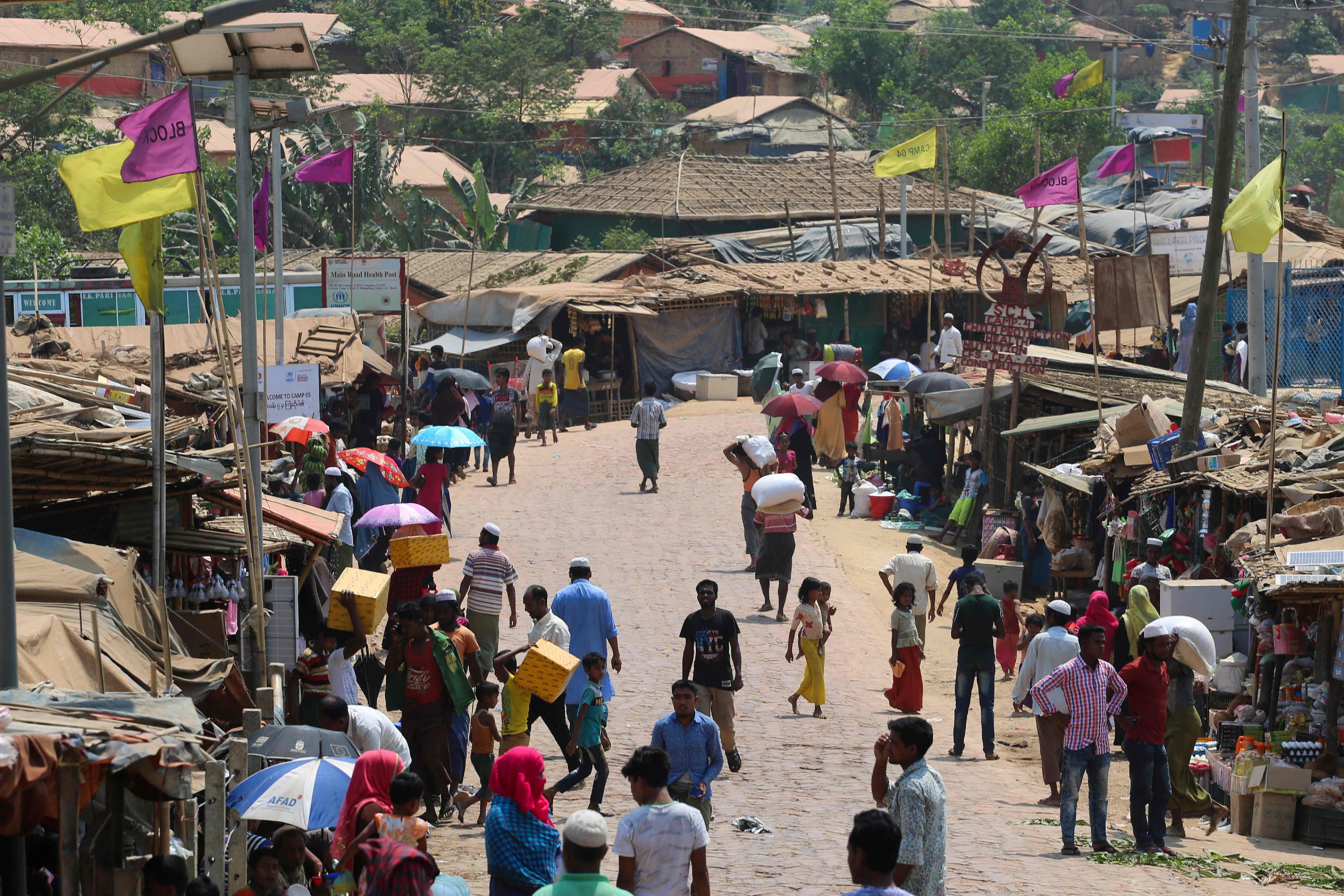 Rohingya refugees, without wearing any mask or any other safty gear as a preventive measure against the COVID-19 novel coronavirus, gather along a market area in Kutupalong refugee camp in Ukhia, (Credit: AFP)