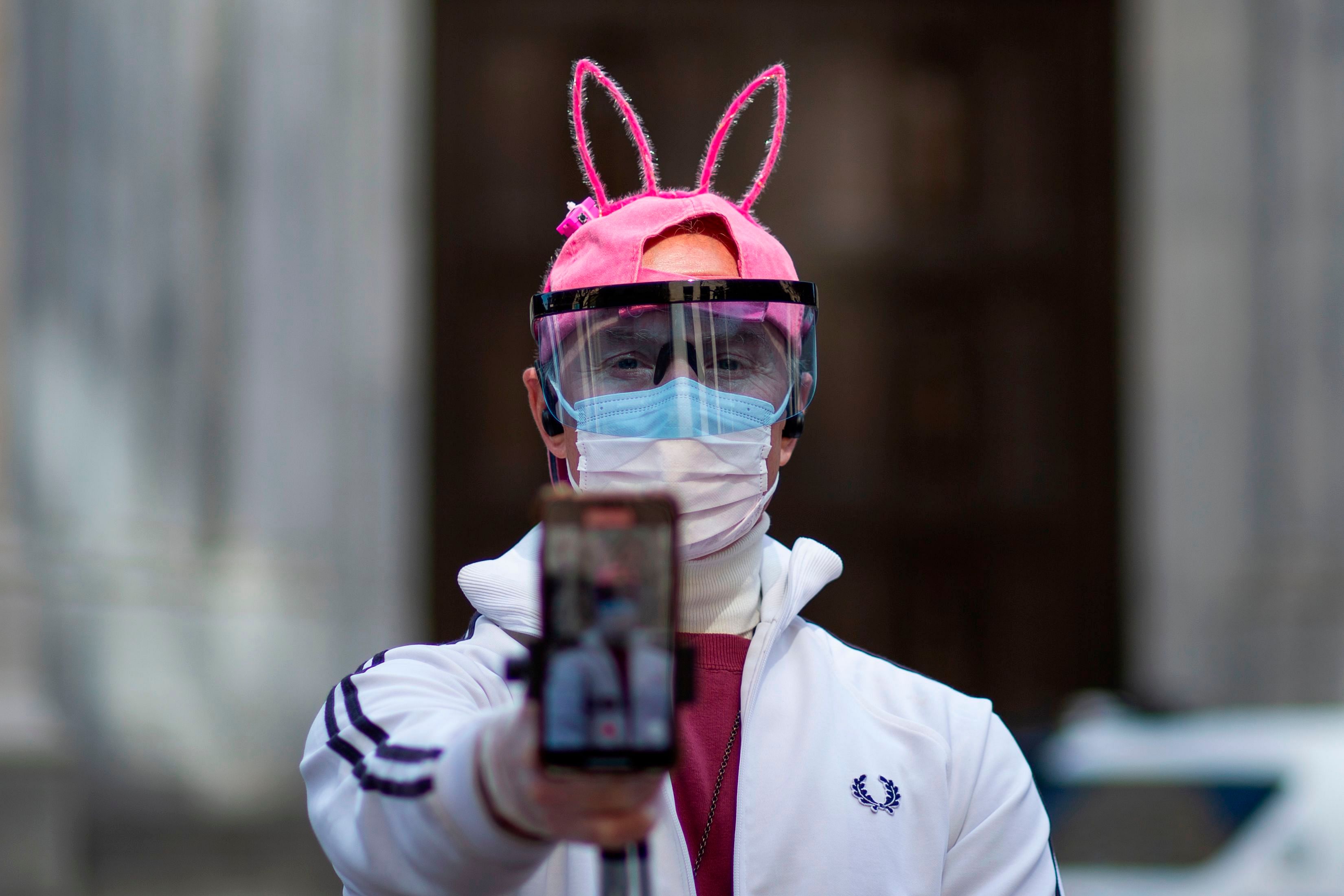 A man wearing bunny ears and face mask records a videos in front of the Saint Patrick Cathedral on Easter. (AFP Photo)