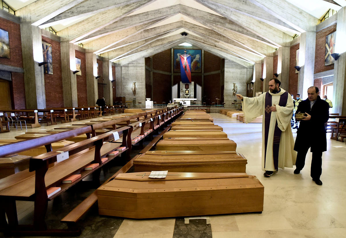  A local priest blesses coffins that have been piling up in a church due to a high number of deaths, before they are taken away by military trucks. Credit: Reuters File Photo
