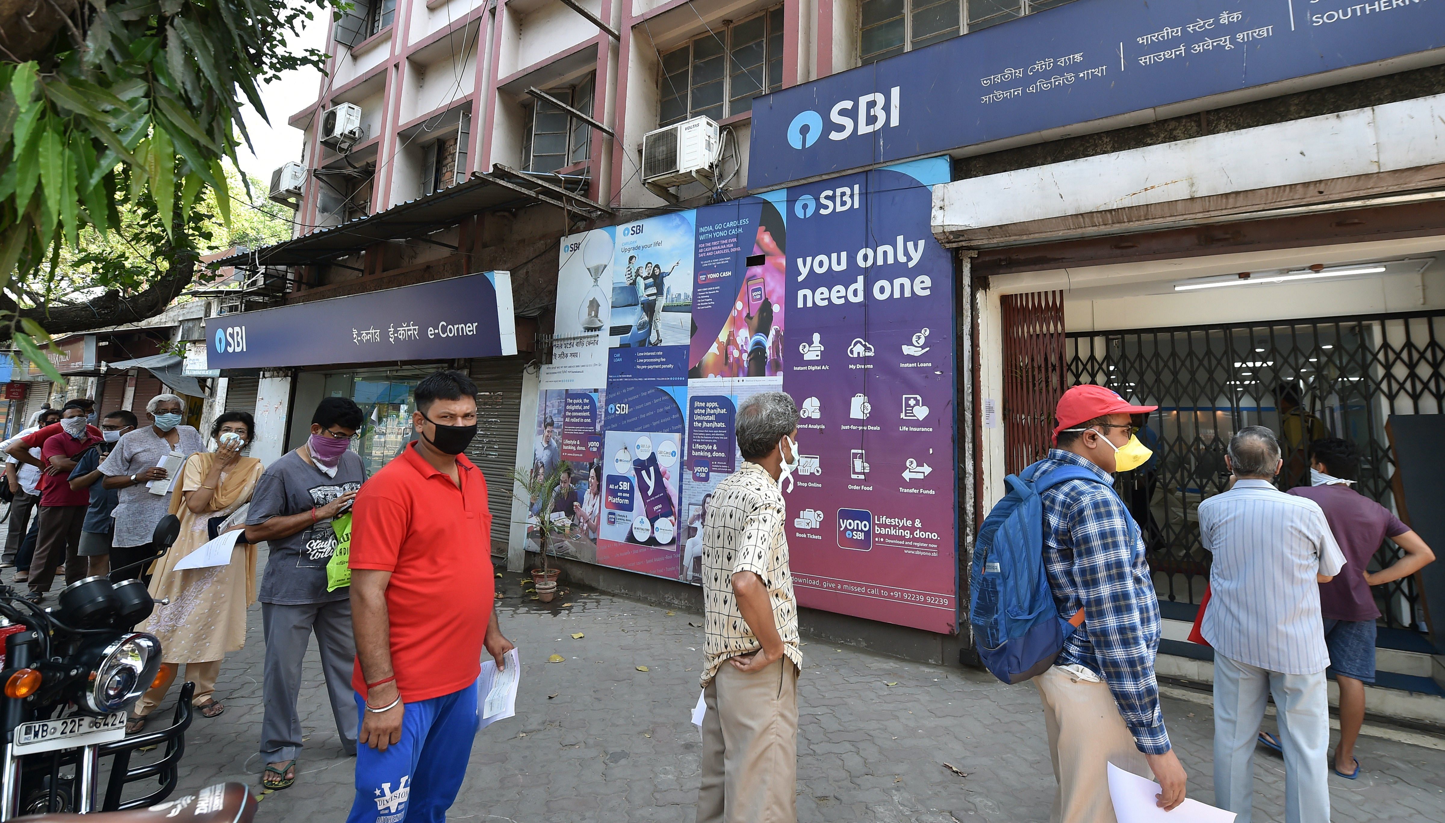People maintain social distance as they stand outside a bank during a nationwide lockdown in the wake of coronavirus pandemic in Kolkata. (PTI Photo)