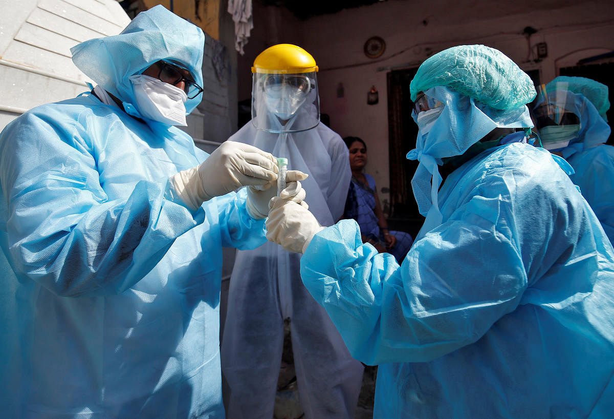 Doctors wearing protective gear seal a vial after taking a swab from a woman to test for coronavirus disease (Reuters Photo)