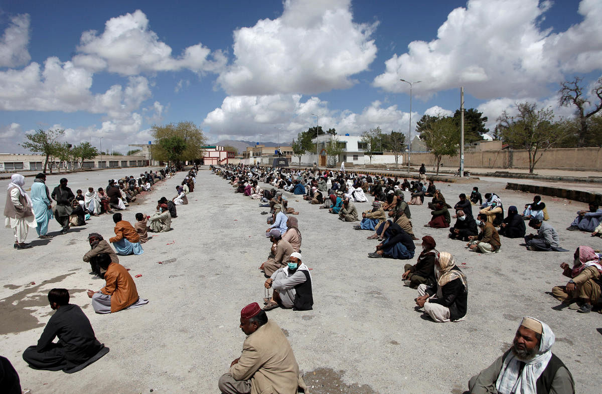 People sit on the ground as they wait to receive sacks of ration handouts from a distribution point of a charity, during a lockdown after Pakistan shut all markets, public places and discouraged large gatherings amid an outbreak of coronavirus disease (COVID-19), in Quetta, Pakistan. (Reuters Photo)