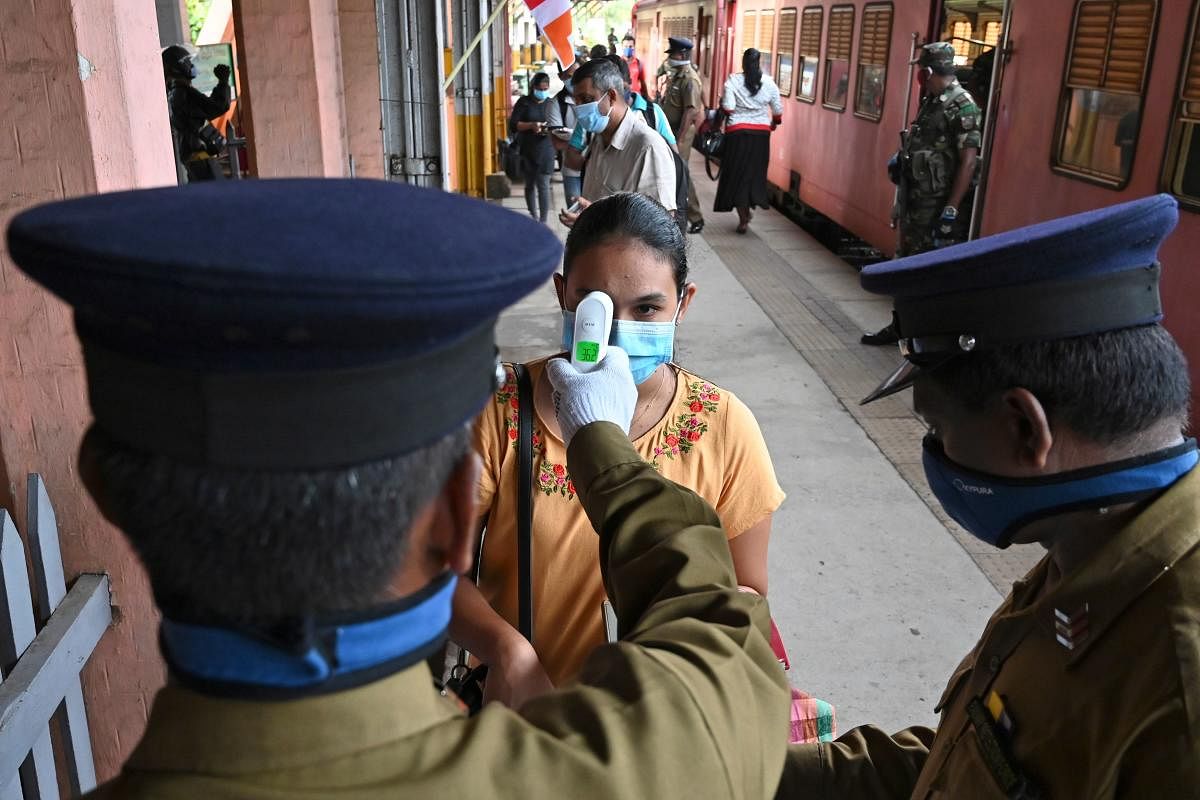 A guard checks the temperature of a government employee in Colombo (AFP Photo)