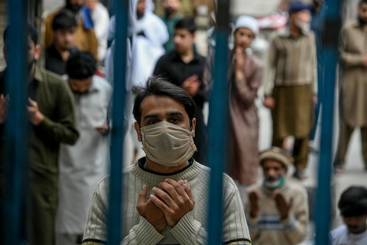 A Muslim worshipper wearing a facemask prays during Friday prayers outside the closed gate of Jamia Mosque during a government-imposed nationwide lockdown as a preventive measure against the COVID-19 coronavirus, in Rawalpindi on April 3, 2020. Credit: AFP Photo