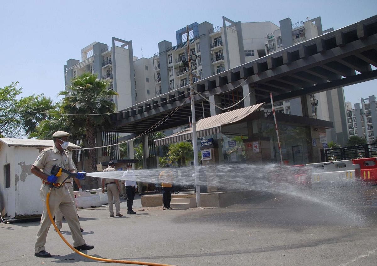  A policeman sprays disinfectant outside a housing society, to curb the spread of coronavirus, during the nationwide lockdown, in Noida, Friday, April 10, 2020. (PTI Photo)