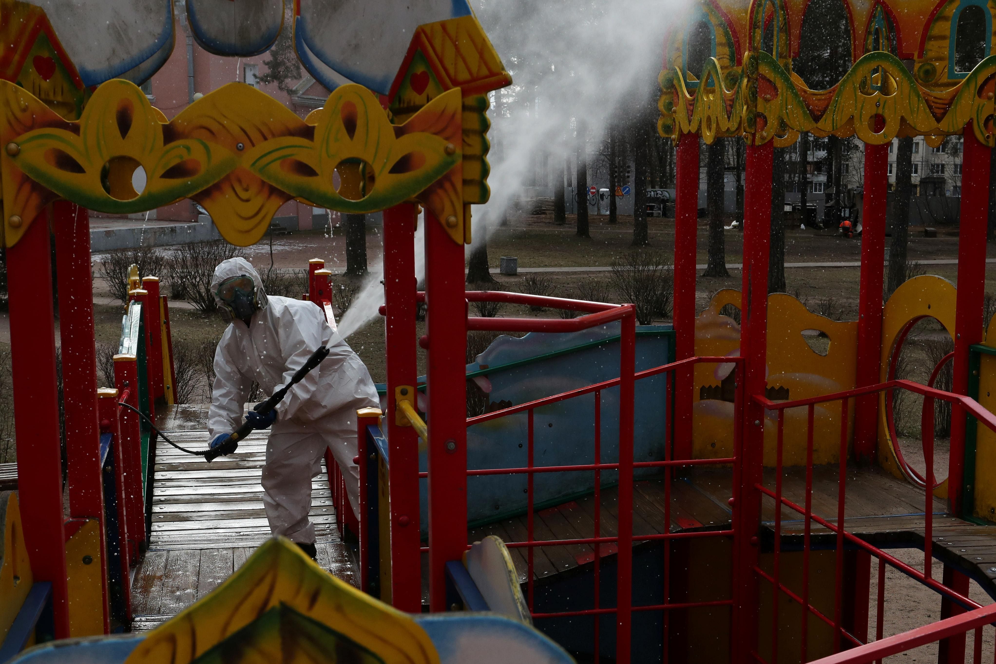 A specialist wearing protective gear sprays disinfectant while sanitizing a playground to prevent the spread of the coronavirus disease (COVID-19) in the town of Vsevolozhsk in Leningrad Region, Russia. (Credit: Reuters)