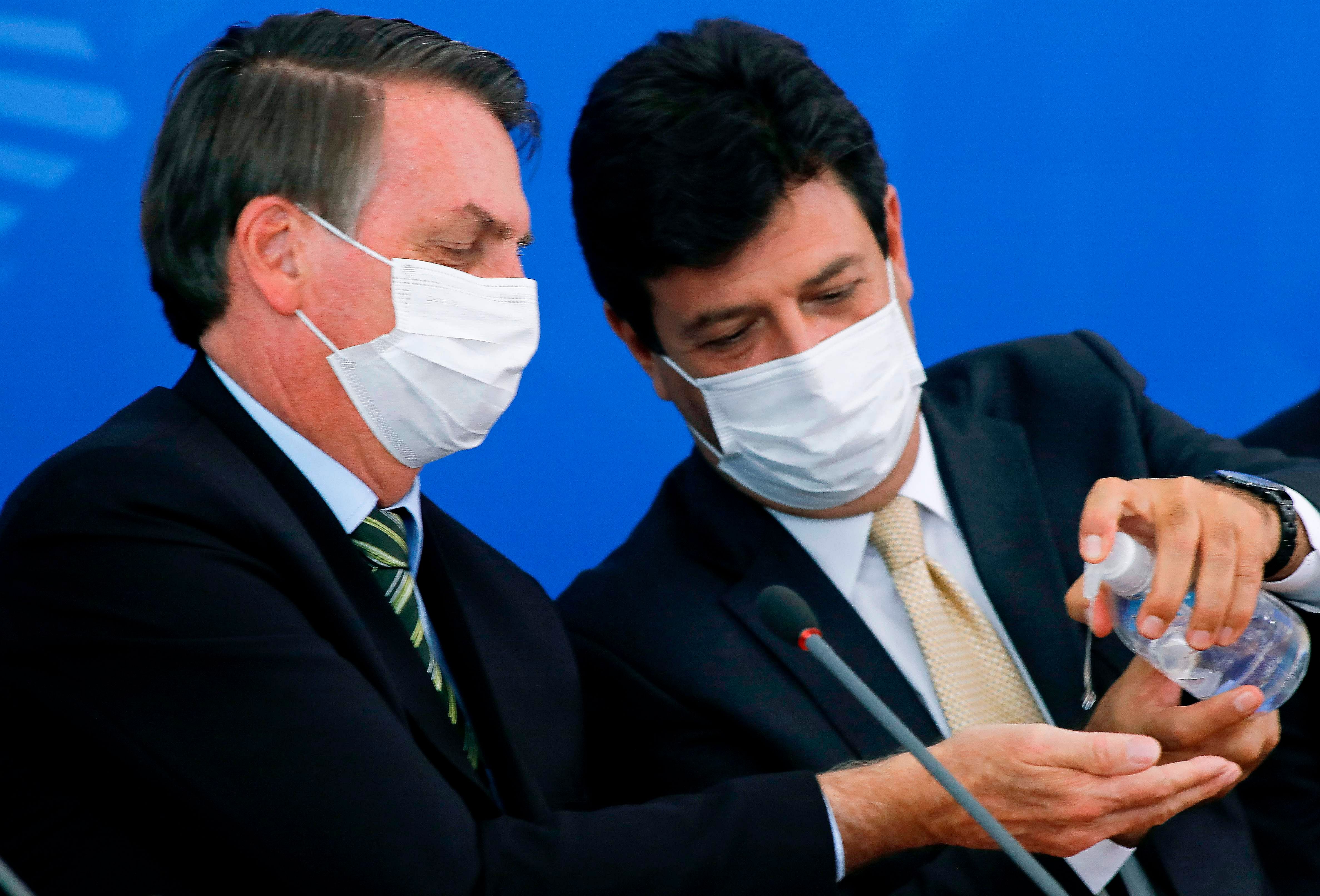 Brazilian President Jair Bolsonaro (L) and former Health Minister Luiz Henrique Mandetta sanitize their hands wearing face masks during a press conference related to the new coronavirus. (AFP file photo)