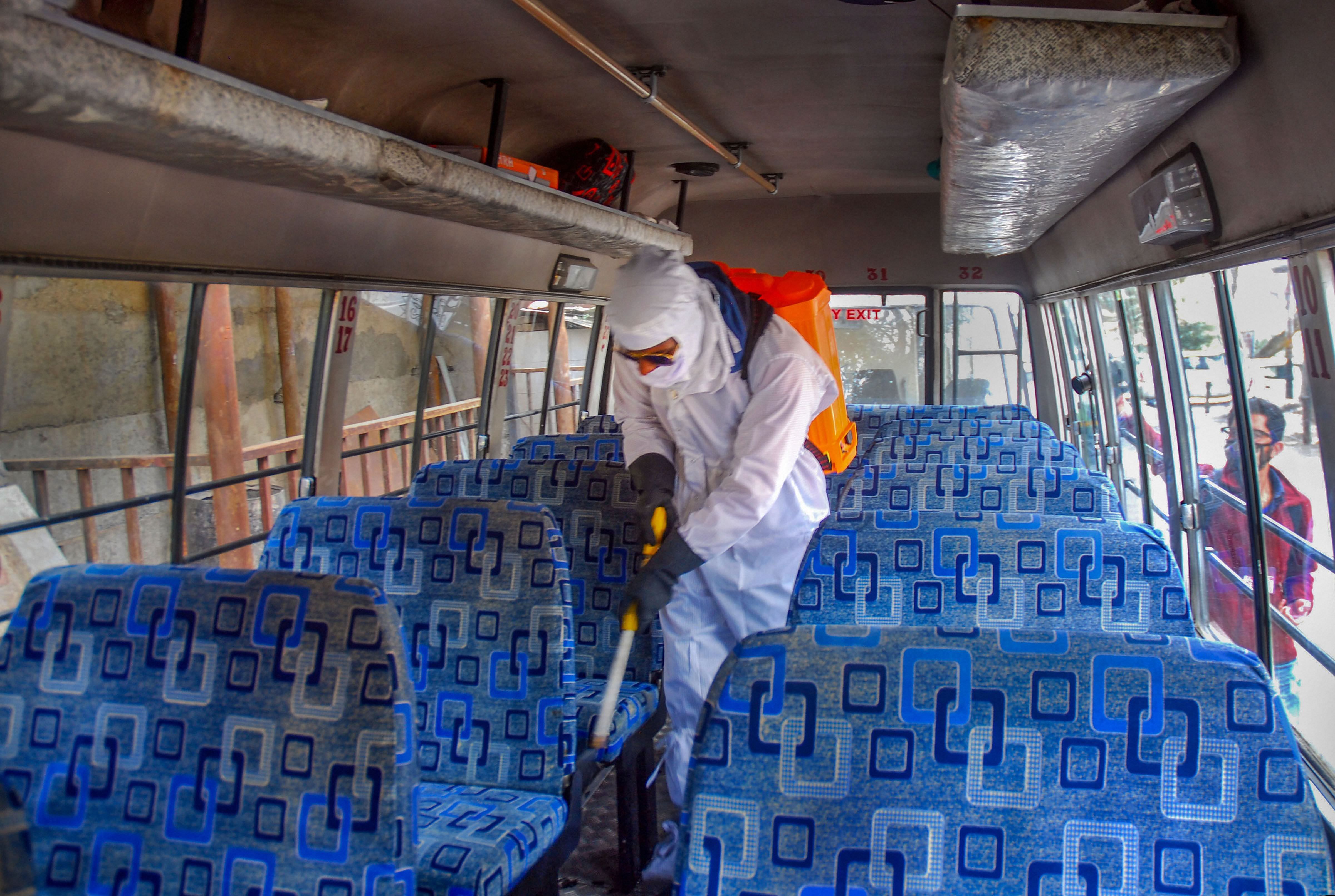 A worker sprays IGMC hospital staff bus after three patients from Nalagarh who were tested positive for Covid-19, had been shifted in the hospital, during a nationwide lockdown in the wake of coronavirus pandemic, in Shimla. (Credit: PTI)
