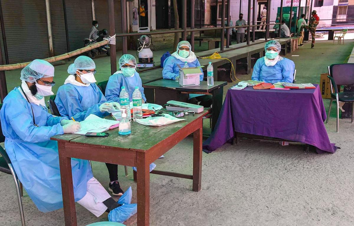  Medics wearing protective suits sit in the premises of Nalanda Medical College Hospital to screen visitors for COVID 19 symptoms, during the nationwide lockdown amid coronavirus outbreak, in Patna (PTI Photo)