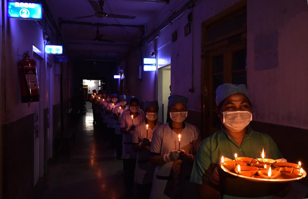 Nurses of JN Ray Hospital hold candles and earthen lamps as a gesture to express their solidarity to mitigate the coronavirus pandemic, during a nationwide lockdown, in Kolkata, Sunday, April 5, 2020. (PTI Photo)