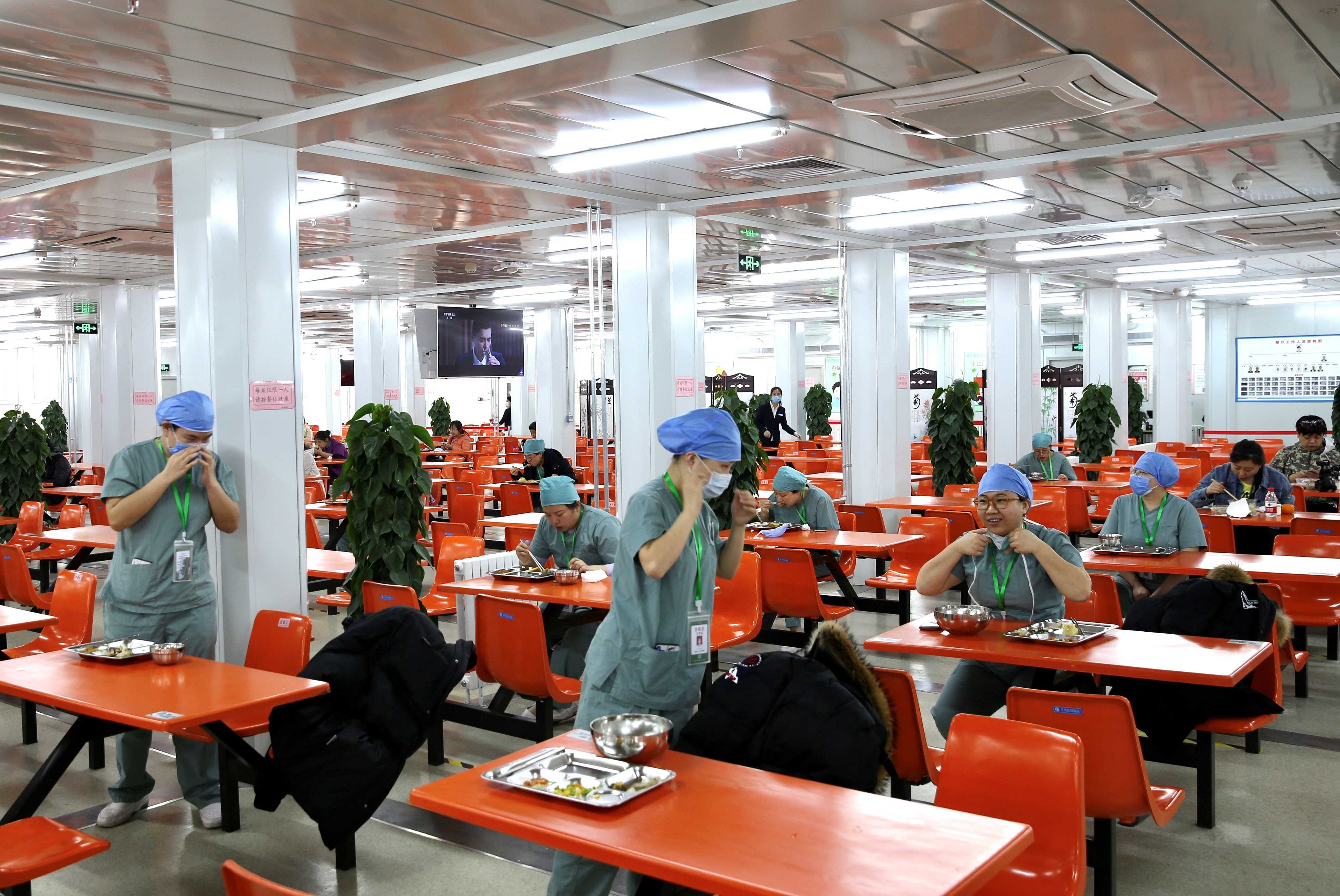Medical workers eat at separate tables at a canteen inside Xiaotangshan Hospital, a hospital built in 2003 to treat patients with Severe Acute Respiratory Syndrome (SARS) that is now used to treat patients with coronavirus disease (COVID-19), in Beijing. (Reuters file photo)