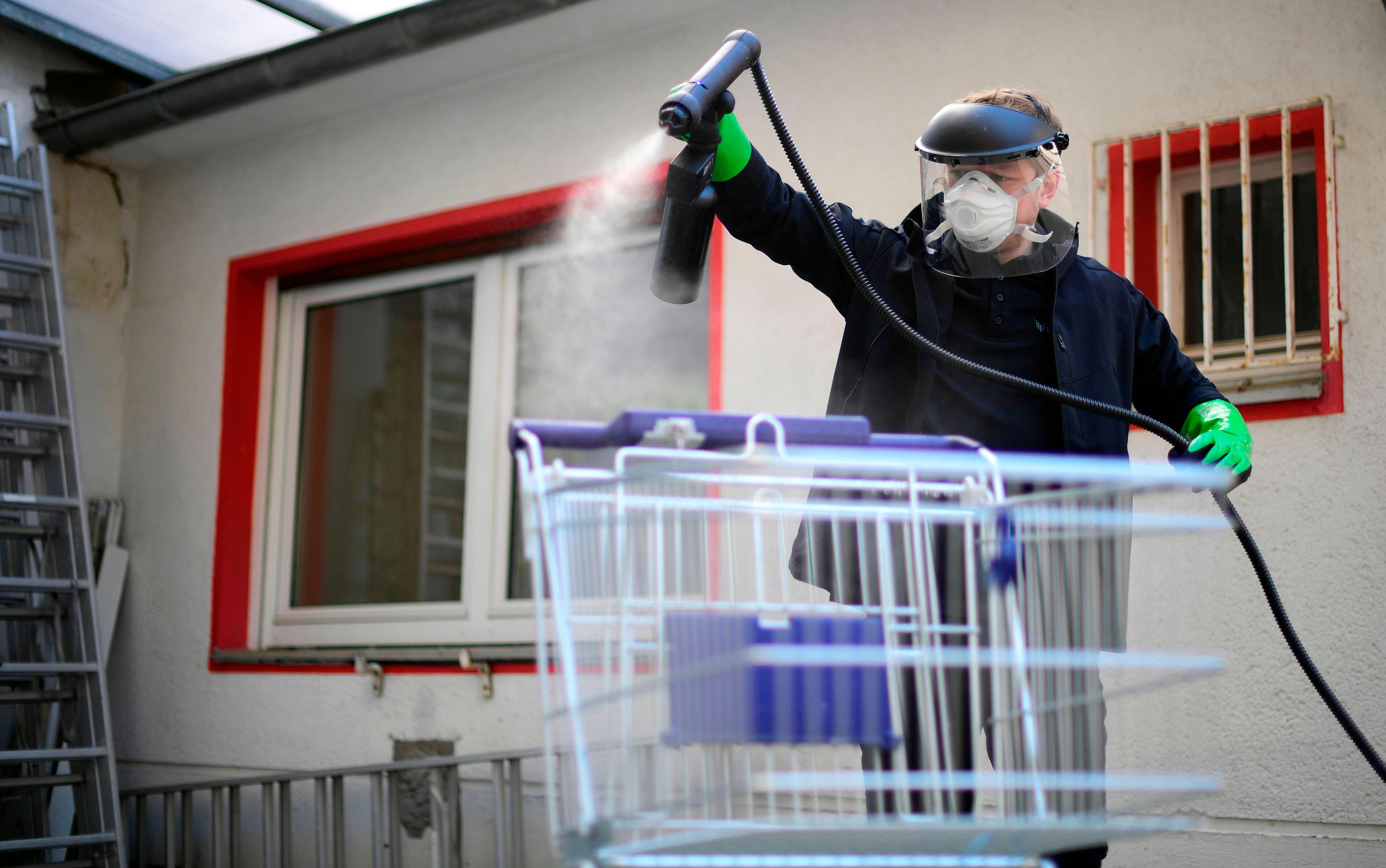 Working student Leon Rottmann coats a shopping trolley for disinfection at the mechanic's workshop of the Startup UVIS UV-Innovative Solutions in Cologne, western Germany. (AFP)