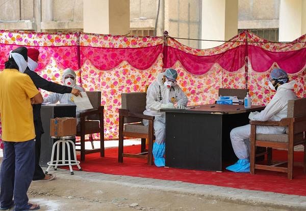 Doctors wearing protective suits as a precautionary measure against the coronavirus check patients outside an isolation ward at Govt. Medical College hospital in Jammu, Monday, April 6, 2020. (PTI Photo) 