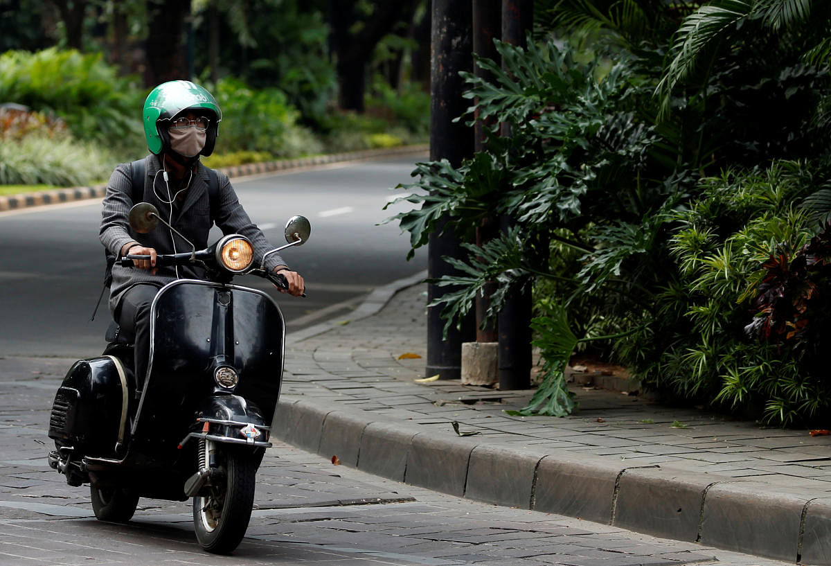 A man wearing a protective mask rides a scooter trough a deserted road during the large-scale restrictions imposed by the government to prevent the spread of the coronavirus disease (COVID-19), in Jakarta, Indonesia, April 25, 2020. Reuters