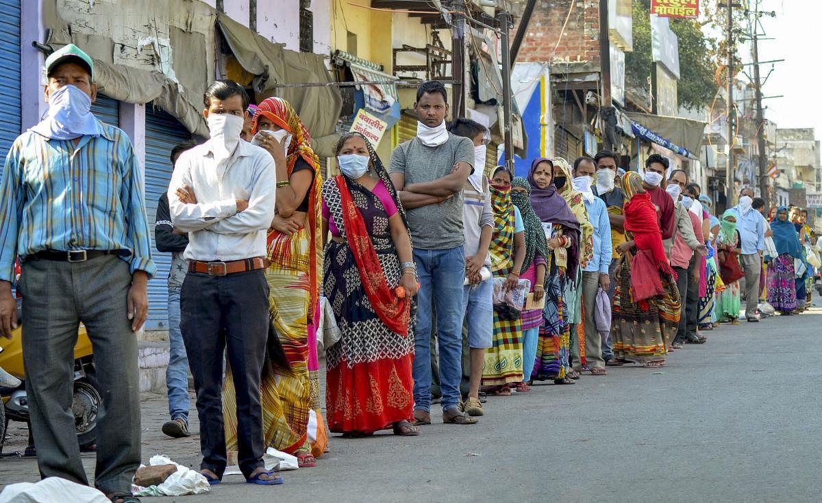  Beneficiaries stand in a queue, wearing face masks, to collect ration at a state government ration centre during the nationwide lockdown amid coronavirus outbreak, in Agra. Credit: PTI Photo