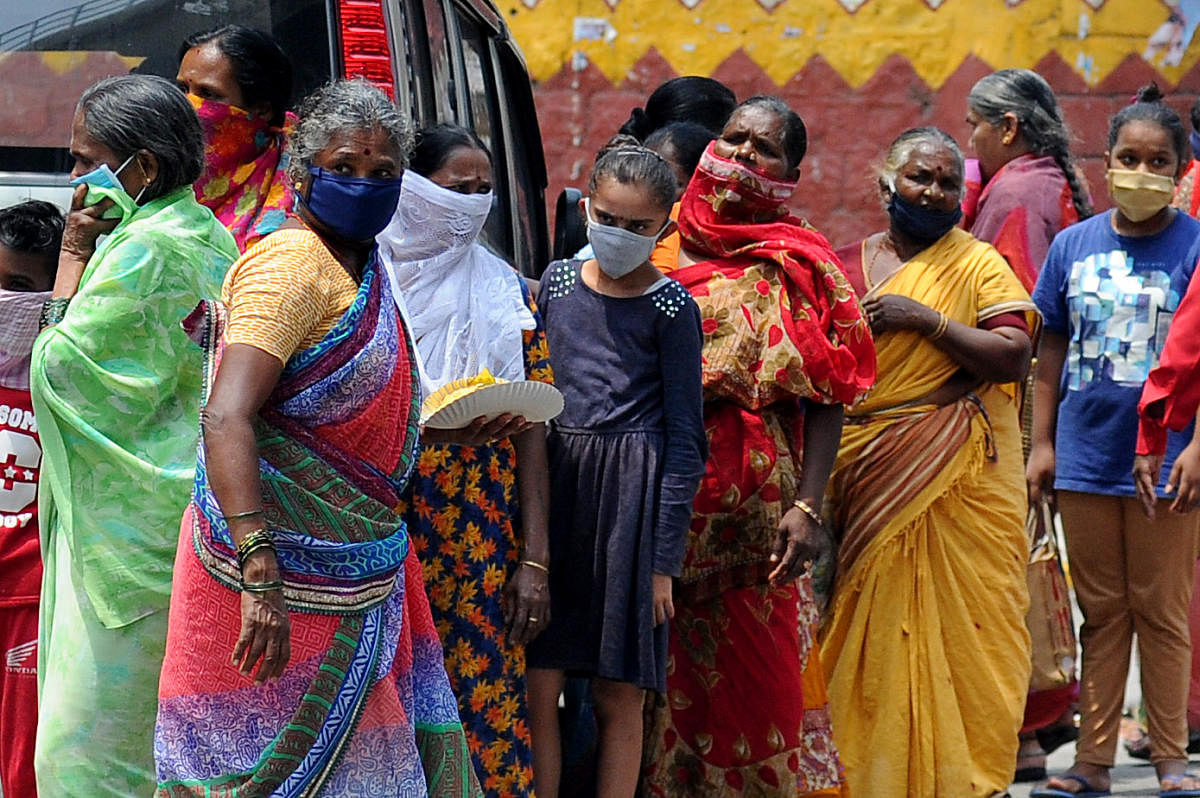 People queue up to collect food at Swami Vivekananda Road, Halasuru, on Friday. DH Photo/Pushkar V