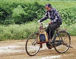H K Ramesh, postmaster at Kundalagurki in Shidlaghatta taluk, travelling from village to village, on bicycle to reach the letters at the addresses. dh photo
