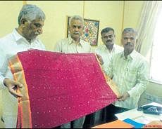 Karnataka Handloom Development Corporation chairman M D Lakshminarayana examining sarees that will be distributed among mothers of girls covered under the Bhagyalakshmi scheme. DH Photo