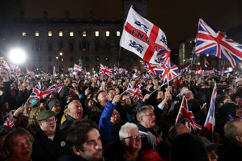 People wave flags as they celebrate in Parliament Square on Brexit day in London. (Reuters Photo)