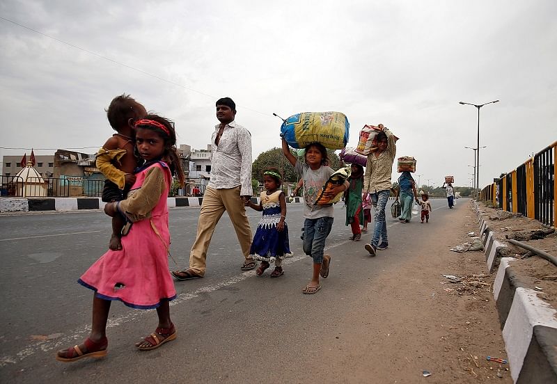 Migrant workers walk with their children as they look out for transport to return to their villages, after India ordered a 21-day nationwide lockdown to limit the spreading of coronavirus disease (COVID-19), in Ahmedabad, India. (Reuters Photo)