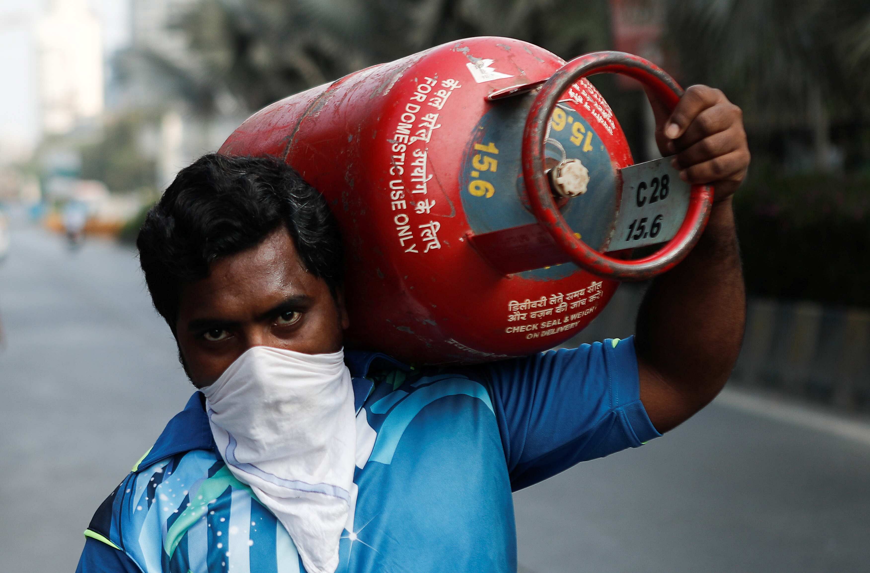 A man carries a gas cylinder as he waits to purchase cooking gas after India ordered a 21- day nationwide lockdown. (Credit: Reuters)