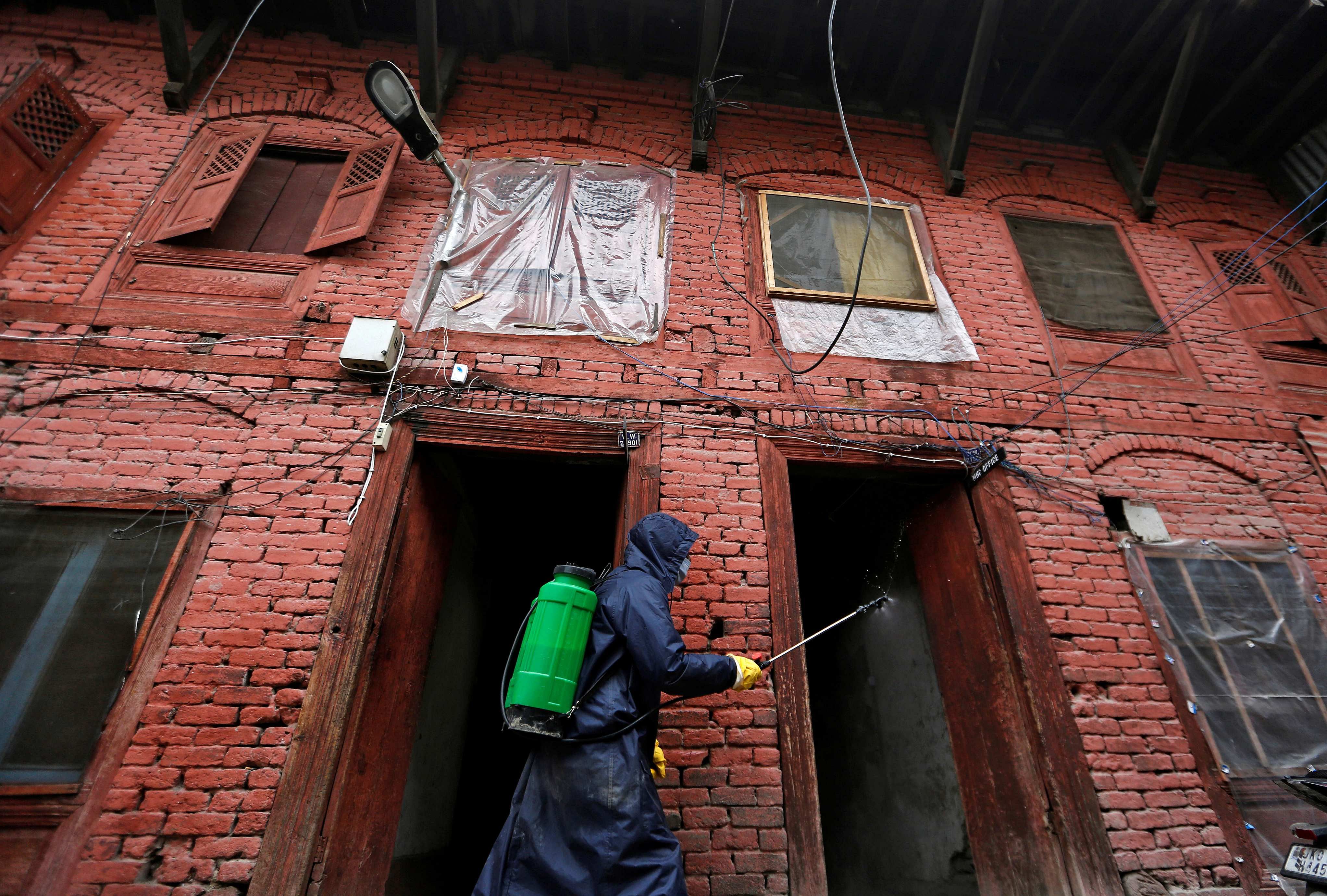 A municipal worker wearing a protective suit disinfects the premises of a police station in Srinagar. (Credit: Reuters)