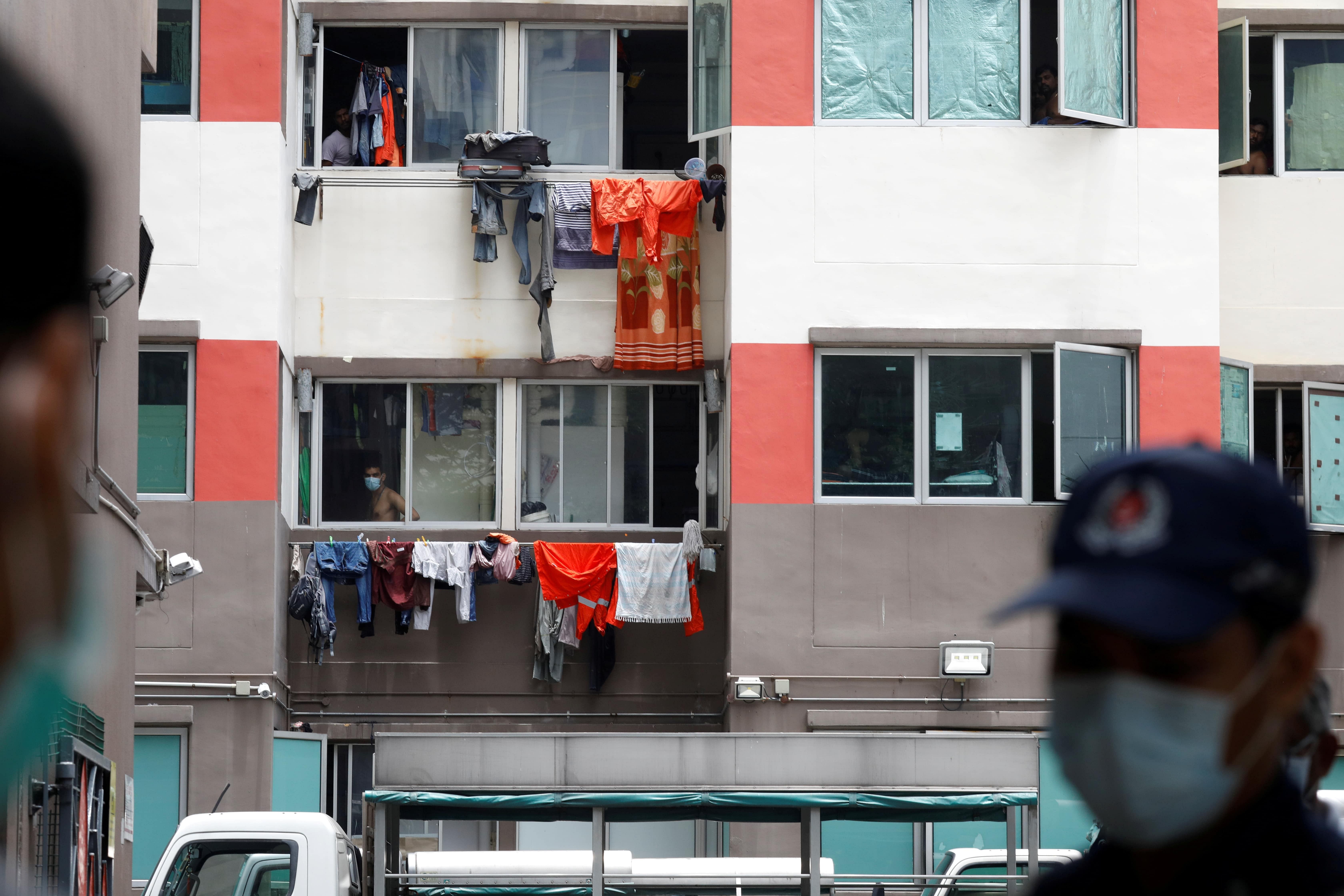 Workers look out of their dorm at Westlite Dormitory, one of the two workers? dormitory gazetted as isolation areas to curb the spread of coronavirus disease (COVID-19) in Singapore. (Credit: Reuters Photo)