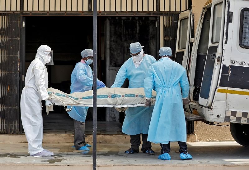 Municipal workers in protective gear carry the body a woman who died due to coronavirus disease (COVID-19). (Reuters Photo)