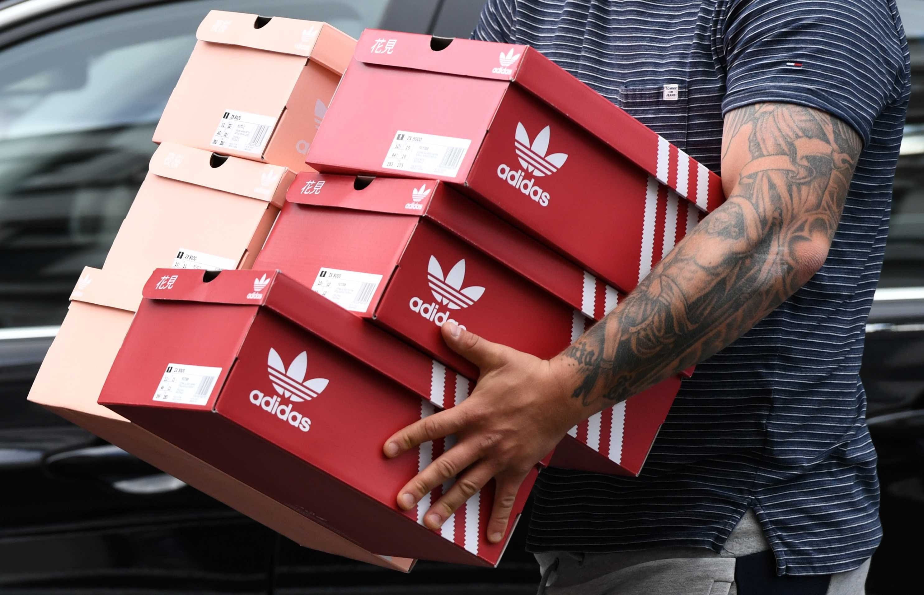 A man carries Adidas shoeboxes near the Adidas store, as the spread of the coronavirus disease (COVID-19) continues, in Berlin, Germany (Credit: Reuters)