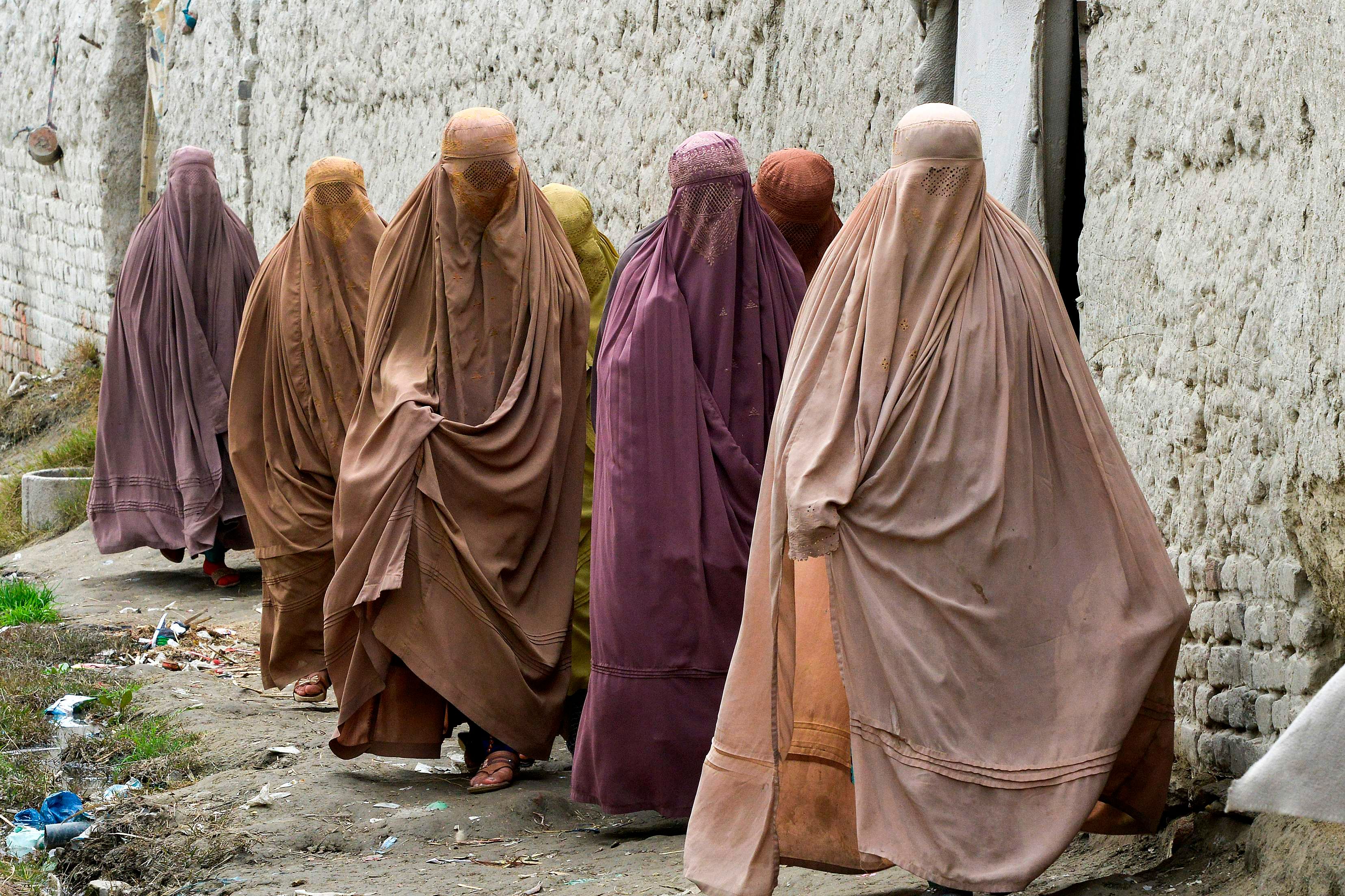 In this picture taken on February 12, 2020, Afghan refugee women walk in a refugee camp in Peshawar.  (Credit: AFP Photo)