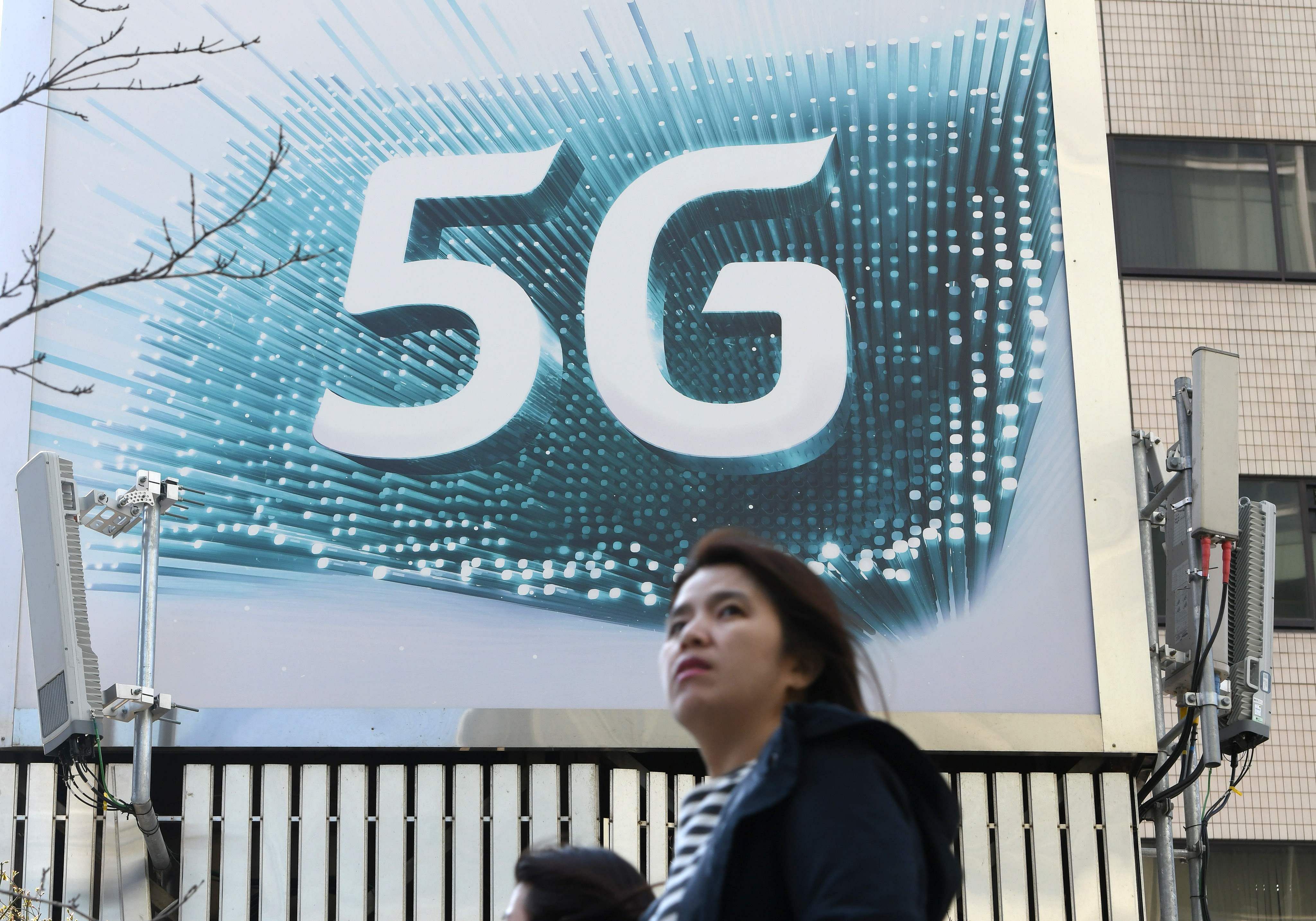A woman walks past an advertisement for the 5G mobile networks service of KT in Seoul. (Credit: AFP)