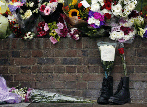 A pair of army boots with floral tributes for Drummer Lee Rigby, of the British Army's 2nd Battalion The Royal Regiment of Fusiliers, are lined at a security fence outside army barracks near the scene of his killing in Woolwich, southeast London May 24, 2013. Police investigating the murder of the soldier on a busy London street are looking into whether the two suspected killers, British men of Nigerian descent, were part of a wider conspiracy. REUTERS