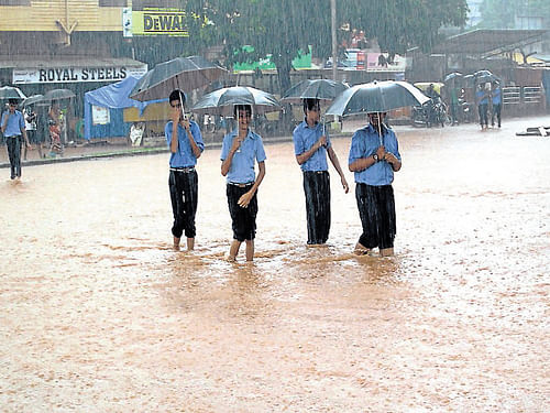 Water, water, everywhere: Schoolchildren wade across a flooded road at Bhatkal in  Uttara Kannada district, on Tuesday. dh photo