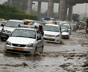 Vehicles moves through a waterlogged road after heavy showers in New Delhi on Monday. PTI Photo