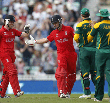 England's Eoin Morgan, left, and Jonathan Trott, center, celebrate their win against South Africa at the end of their ICC Champions Trophy semifinal cricket match at the Oval cricket ground in London, Wednesday, June 19, 2013.  AP Photo.
