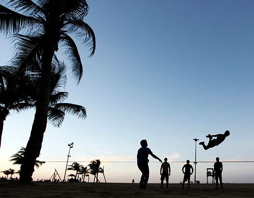 People are silhouetted against the sun as they practise slacklining at a beach in Fortaleza. Reuters File Photo