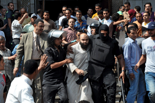 Egyptians security forces escort an Islamist supporter of the Muslim Brotherhood out of the al-Fatah mosque, after hundreds of Islamist protesters barricaded themselves inside the mosque overnight, following a day of fierce street battles that left scores of people dead, near Ramses Square in downtown Cairo, Egypt, Saturday, Aug. 17, 2013. Authorities say police in Cairo are negotiating with people barricaded in a mosque and promising them safe passage if they leave. Muslim Brotherhood supporters of Egypt's ousted Islamist president are vowing to defy a state of emergency with new protests today, adding to the tension. AP photo