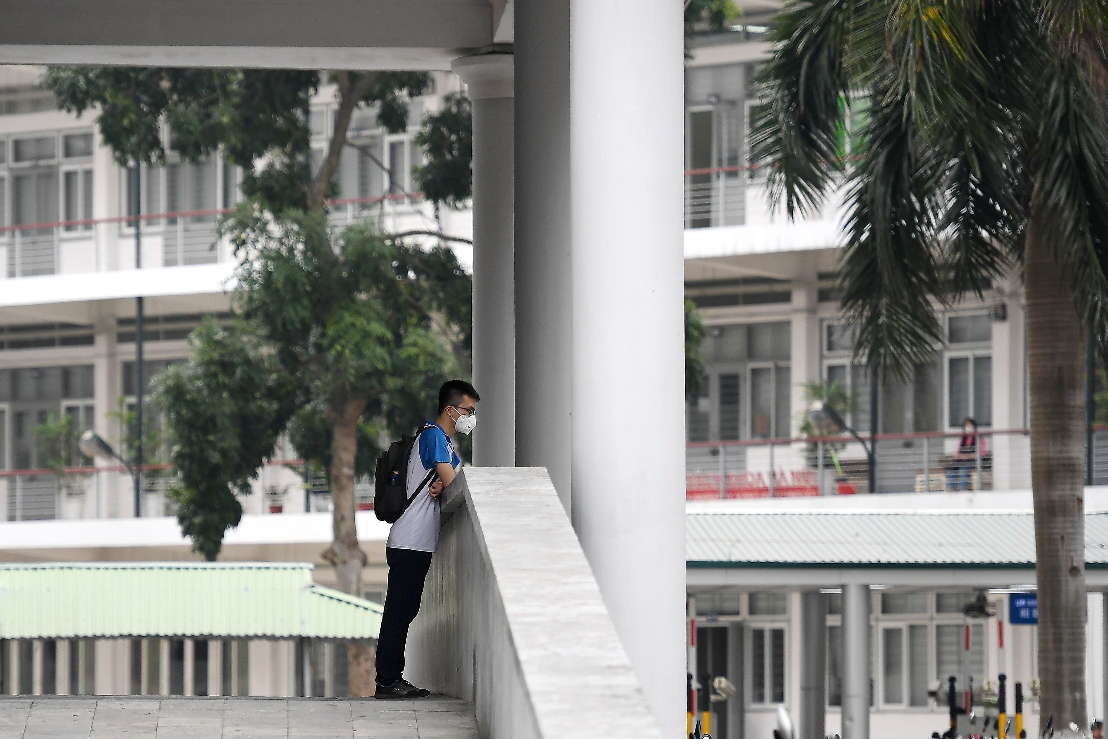 A student, wearing a facemask amid concerns of the COVID-19 novel coronavirus outbreak, stands in the University of Science and Technology campus in Hanoi, (Credit: AFP)