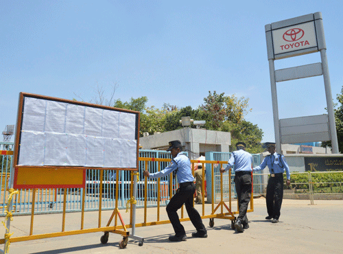 Private security guards move a barricade outside a closed plant of Toyota Motor Corp's India unit near Bangalore. Toughening its stand against agitating employees, Toyota India has suspended 17 workers for misconduct and indiscipline four days after it declared a lockout in its twin factories near here. Reuters photo