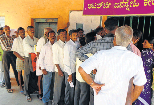 Farmers wait in queue in front of Nemmadi Kendra, in Kushalnagar, on Tuesday, to get RTCs. DH Photo